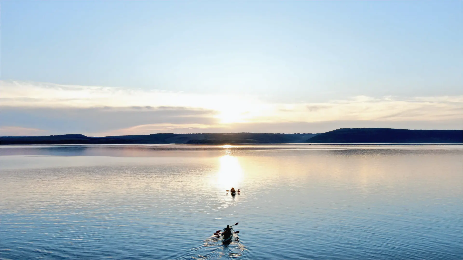 A kayak silhouetted on calm water at sunset